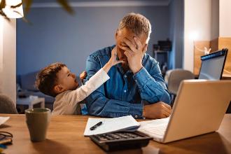 
		A stressed father sits at his laptop with his son
	